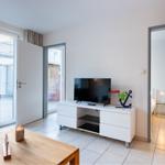 Wohnzimmer mit TV, Couch und Blick auf Balkon. Durchgang zur Schlafzimmer.