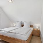 Schlafzimmer mit Doppelbett, Nachttisch und Fenster mit Blick auf Grün.