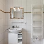Badezimmer mit Waschbecken, Spiegel und Heizkörper an der Wand.