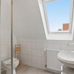 Badezimmer mit Dusche, Toilette und Waschbecken unter Dachfenster