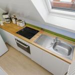 Küche mit Dunstabzug, Kühlschrank, Herd und Spüle unter Dachfenster.