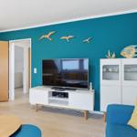 Wohnzimmer mit blauer Wand, Fernseher, Schrank und Sofa.