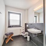 Badezimmer mit Waschbecken, Toilette, Dusche und Fenster