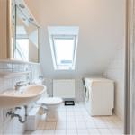 Badezimmer mit Waschmaschine, Toilette und Dachfenster.