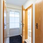 Hinter dem Eingang befindet sich ein Badezimmer mit Toilette und Fenster mit Jalousie.
