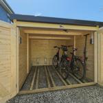 Holzgarage mit zwei Fahrrädern und Dachüberstand