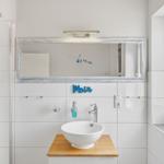 Badezimmer mit Dusche, Waschbecken und Fenster