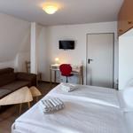 Ein Schlafzimmer mit Doppelbett, Sofa, Schreibtisch und Fernseher.
