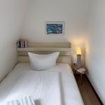 Ein Schlafzimmer mit einem Bett, einer Lampe und Wandbildern.