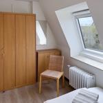 Schlafzimmer mit Dachschrägen, Kleiderschrank, Stuhl und Fenster.
