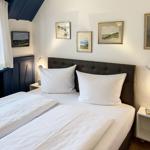 Schlafzimmer mit Doppelbett, Wandbildern und Nachttischen mit Lampen.
