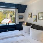 Schlafzimmer mit Bett, Fenster und Wandbildern.