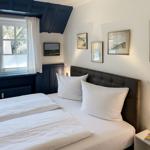 Schlafzimmer mit Doppelbett, Fenster und Wandbildern.