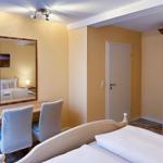 Schlafzimmer mit Bett, Schreibtisch, Spiegel und Kleiderschrank.