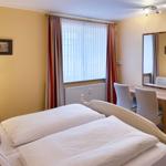 Zimmer mit Doppelbett, Schreibtisch und Spiegel an der Wand.
