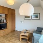 Living room with sofa, wooden furniture, and TV under sloped ceiling.