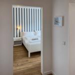 Bedroom with bed and striped wall. Adjacent room with sink.