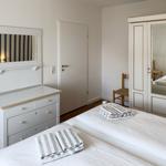 Two beds with towels, wardrobe with mirrored doors, and vanity with mirror.