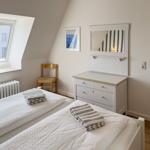 Room with two beds, dresser, and skylight. Wooden chair and radiator are present.