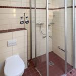 Bathroom with shower, toilet, and tiled floor.