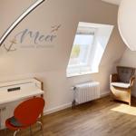 Bedroom with desk, chair, and armchair under sloped ceilings. Wall decoration with sea motif.
