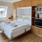 Bedroom with double bed, window, TV, and wooden furniture.