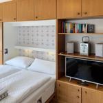 Bedroom with bed, bookshelf, and TV in wooden cabinet.
