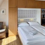 Room with double bed, wooden furniture, and TV. A picture hangs on the wall.