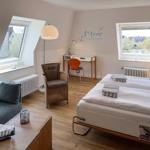 Room with double bed, sofa, desk, and two windows with views.