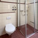 Bathroom with shower, toilet, and tiled floor.