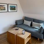 A gray sofa with cushions and wooden table under sloped walls.