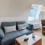 A living room with gray sofa, wooden table, and seating under sloped ceilings.