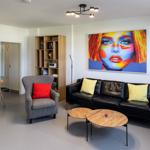 Living room with sofa, armchair, table, and wall art