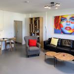 Living room with sofa, armchair, table, and wall art.