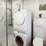 Badezimmer mit Dusche, Waschmaschine und Trockner. Wandbild mit Leuchtturm.