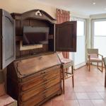 Holzschrank mit Fernseher, Sitzgelegenheiten und Fenster mit Jalousien.
