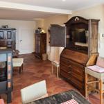 Wohnraum mit Holzmöbeln, Kaminofen und Fernseher in Schrank. Terrakottafußboden und Gittervorhänge.