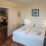 Schlafzimmer mit Doppelbett, Bettwäsche und Blick in Wohnbereich.