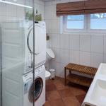 Waschmaschine und Trockner in Bad mit Waschbecken und Holzbank.