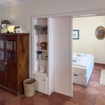 Ein Raum mit Holzschrank und Regal, Tür zum Schlafzimmer mit Bett und Spiegel.