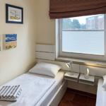 Zimmer mit zwei Betten, Fenster und Wandbildern