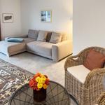 Wohnzimmer mit Eckcouch, Rattan-Stuhl und orientalischem Teppich.