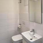 Badezimmer mit Toilette, Waschbecken und Spiegel.