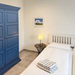 Zimmer mit Doppelbett, blauem Schrank und Nachttisch mit Lampe.