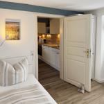 Schlafzimmer mit Bett, Wandbild und Tür zur Küche.
