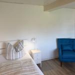 Ein Schlafzimmer mit Bett, Nachttisch und blauer Sessel.