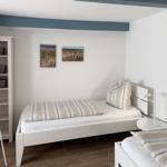 Zimmer mit zwei Betten, weißen Möbeln und Wandbildern