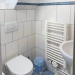 Badezimmer mit Toilette, Waschbecken und Heizkörper an der Wand.