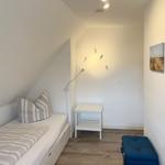 Schlafzimmer mit Bett, Tisch und Wandbildern.