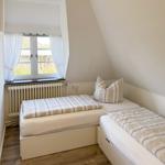 Zimmer mit zwei Einzelbetten, Fenster und Heizkörper.